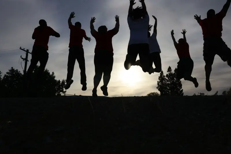 The Action Fitness crew jumping together, silhouetted against the sky