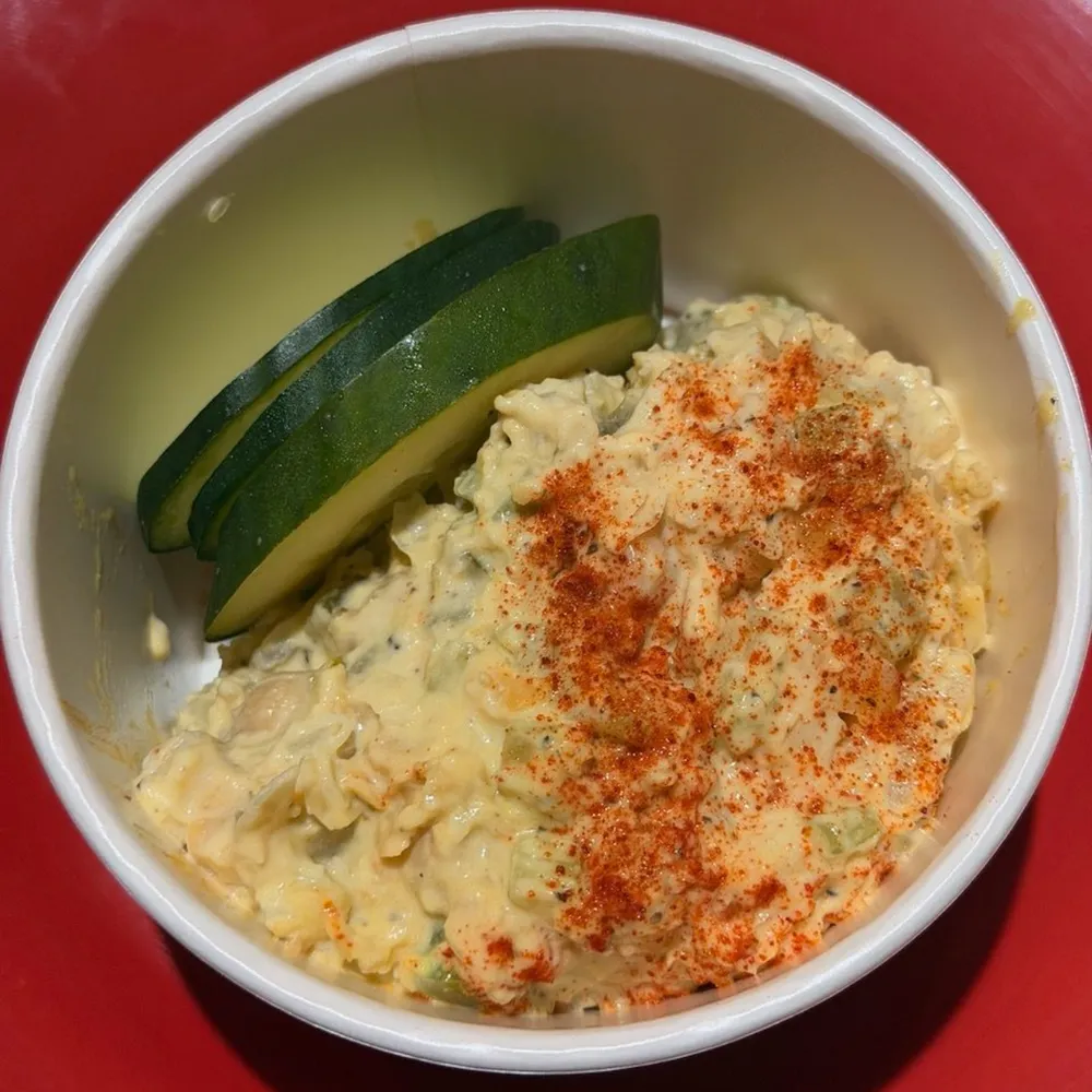 A bowl of The Check Up chickpea salad topped with paprika and cucumber slices