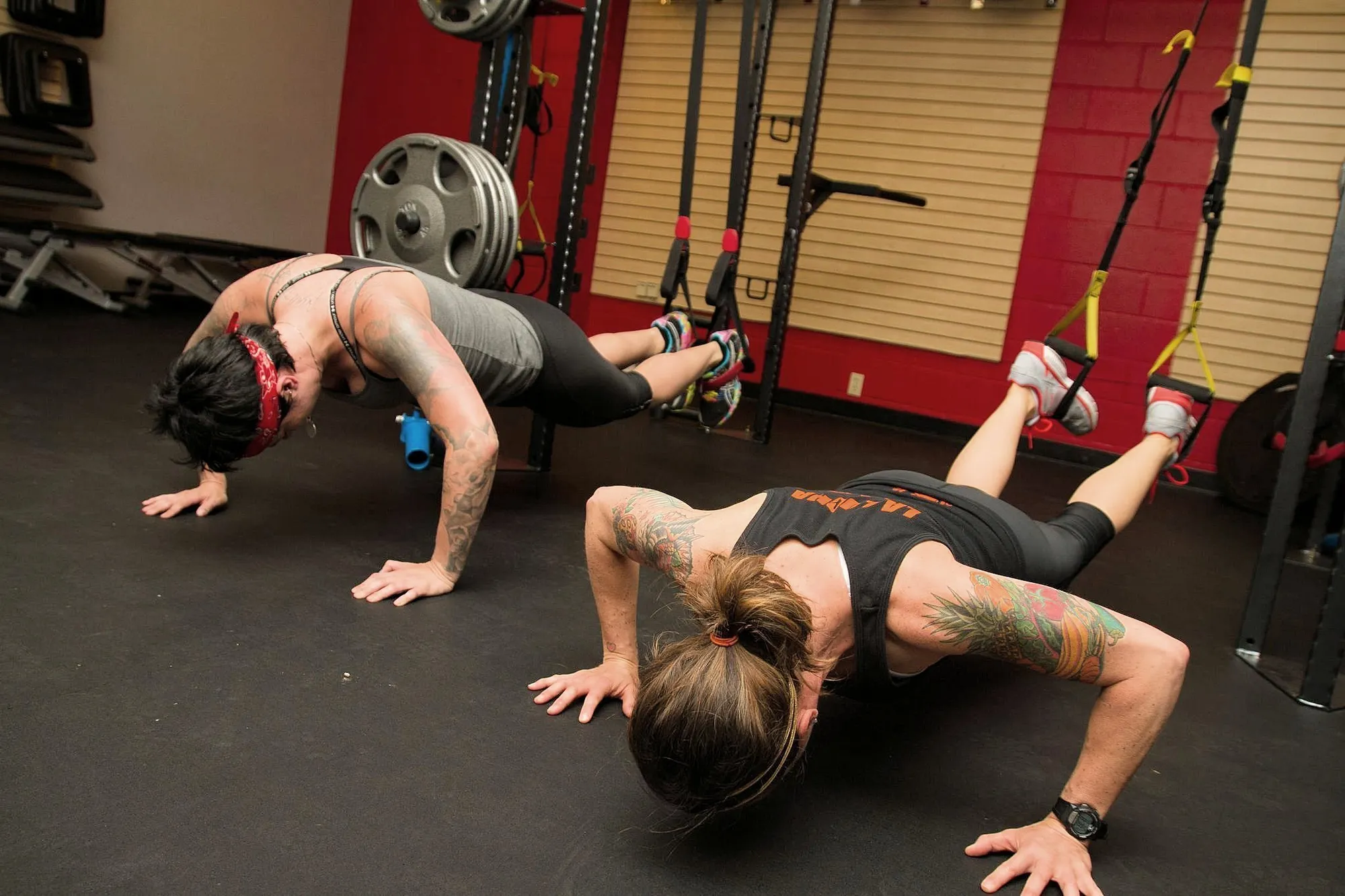 Two members doing push-ups with their feet in the suspension straps