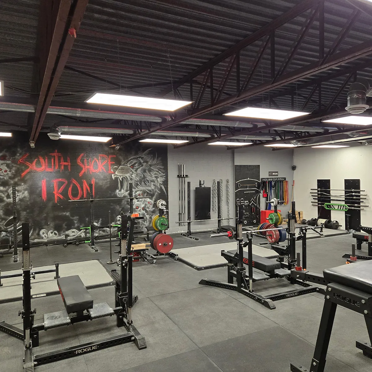 Rows of Rogue squat racks and benches under the South Shore Iron mural