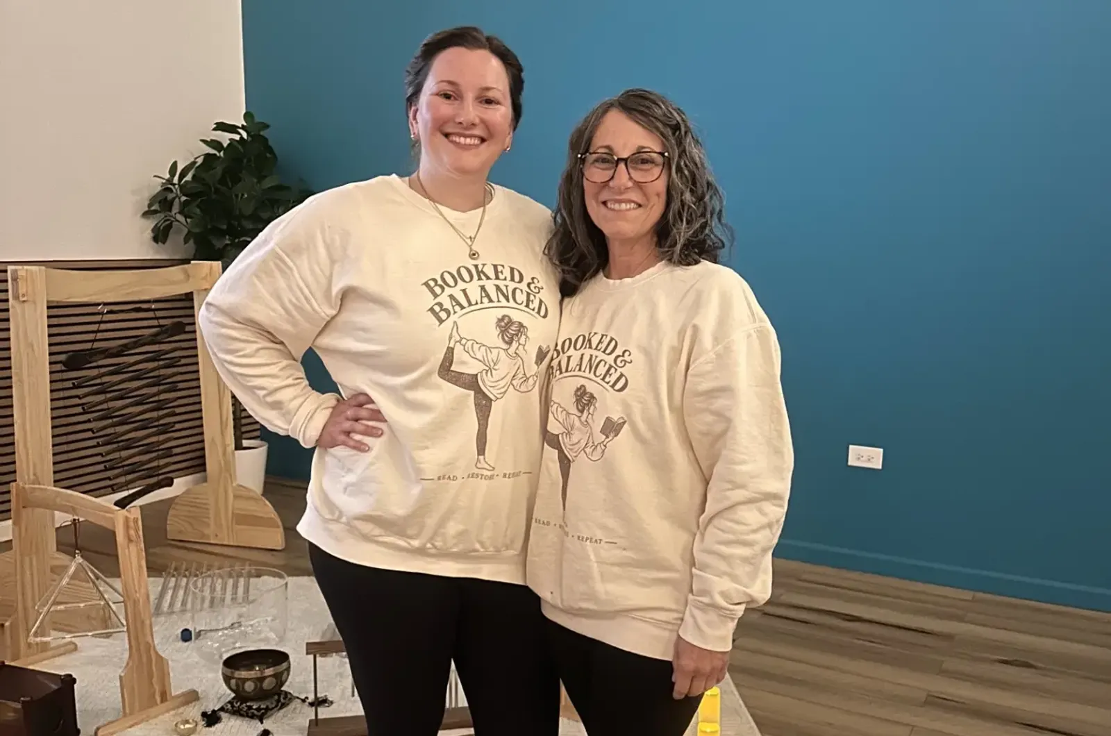 Two Teal Yogi teachers smiling in the studio in matching sweatshirts