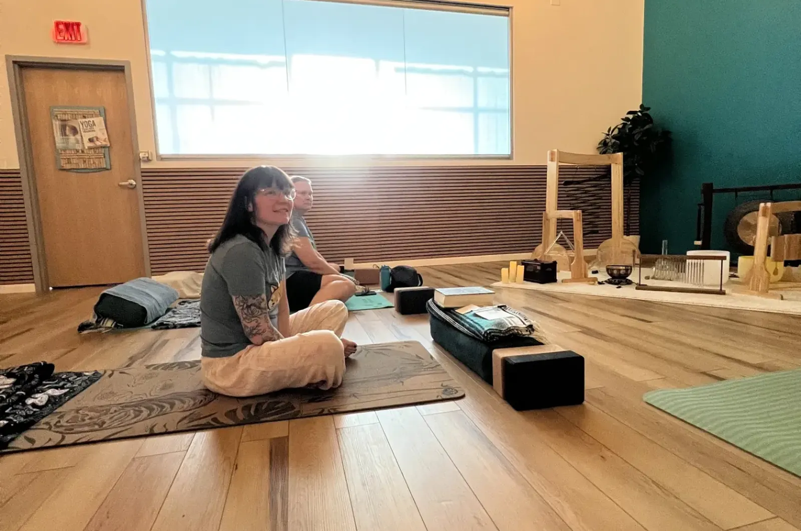 A student sitting cross-legged on her mat in the morning light
