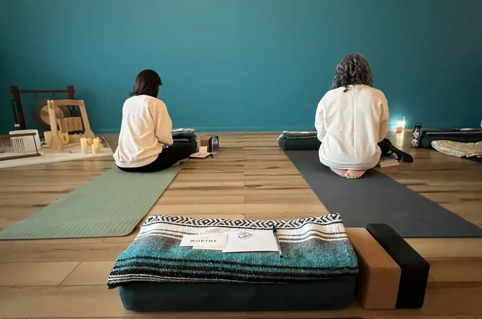 Two students settling onto their mats with bolsters and blankets