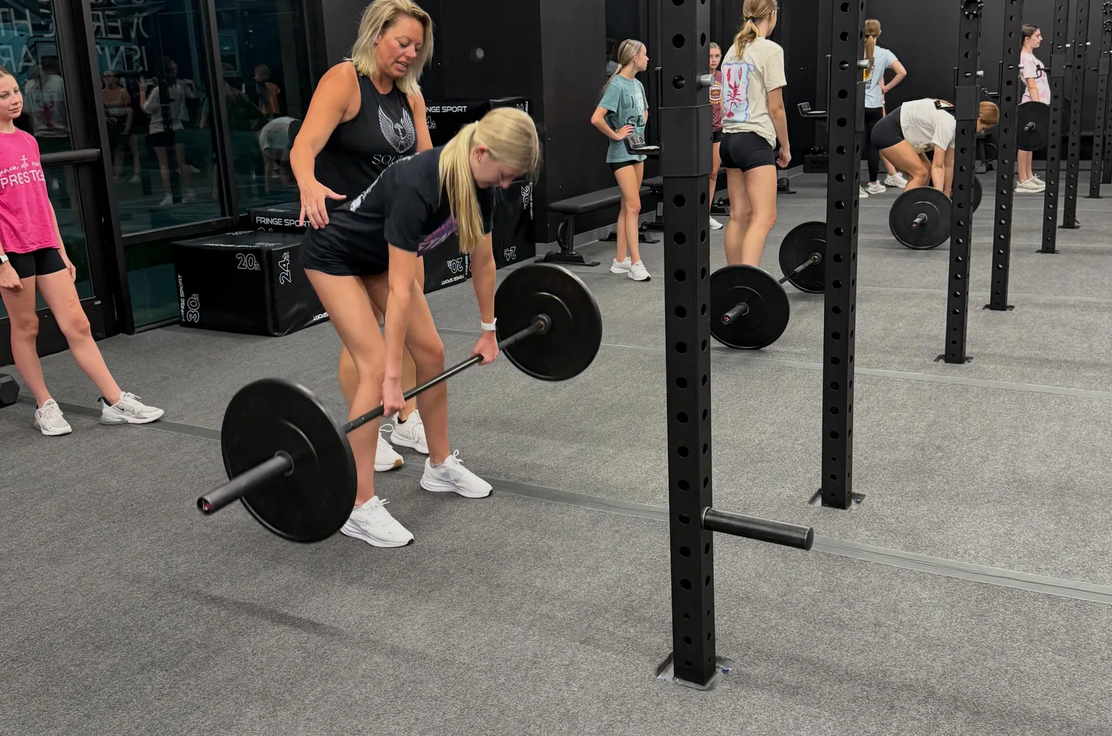 A coach guiding a member through a barbell deadlift during a Valkyrie Society class