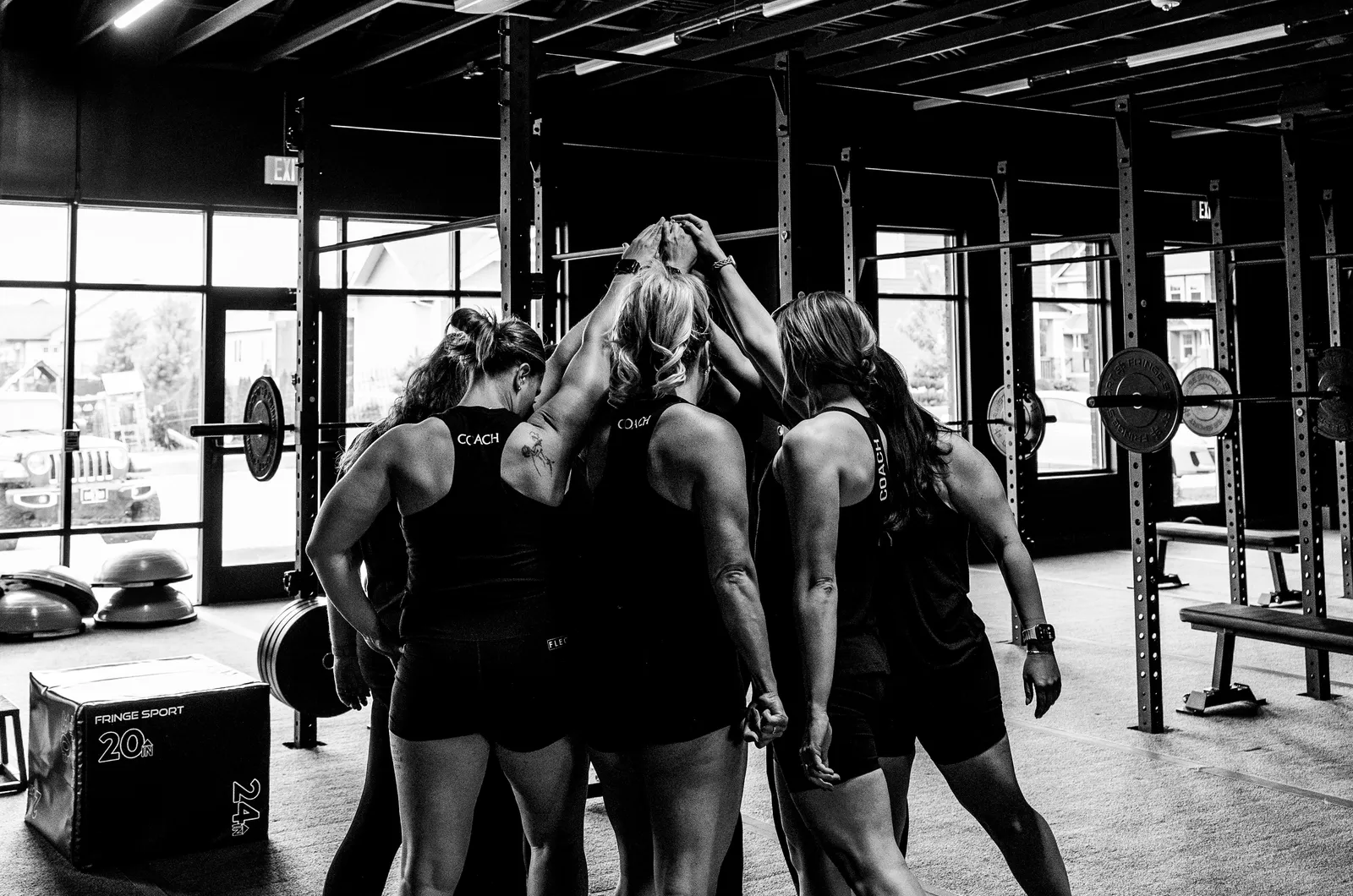 Members in a tight huddle between the lifting racks, in black and white