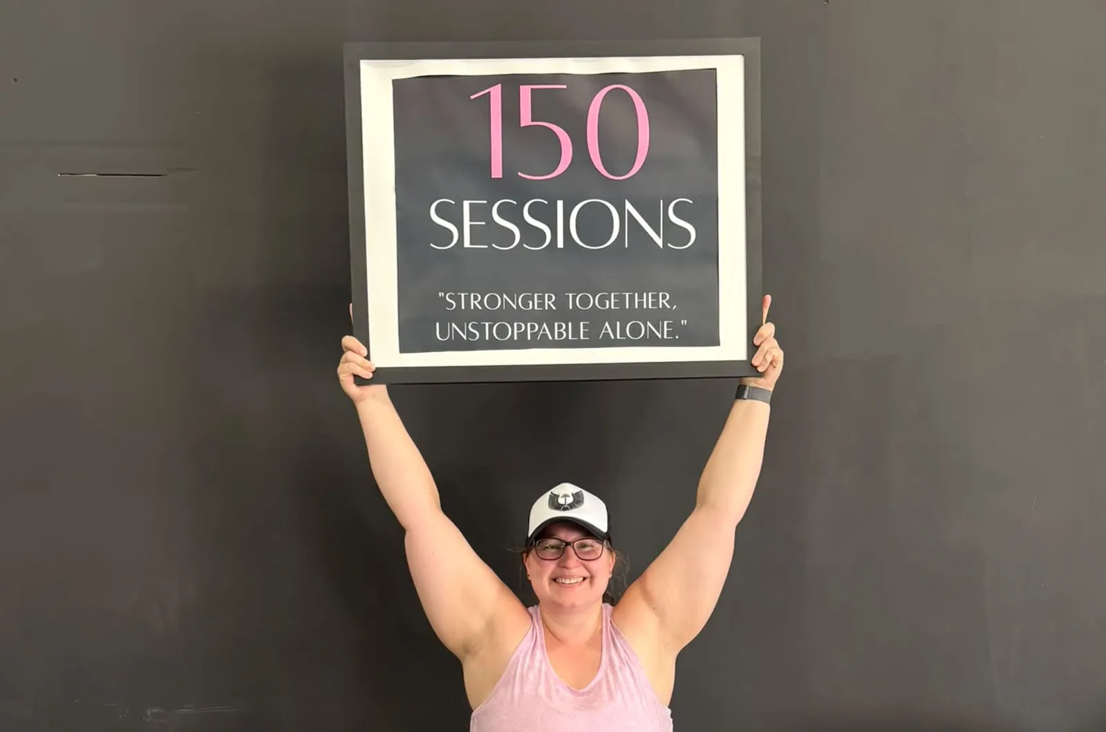 A member holding a 150 sessions milestone sign above her head